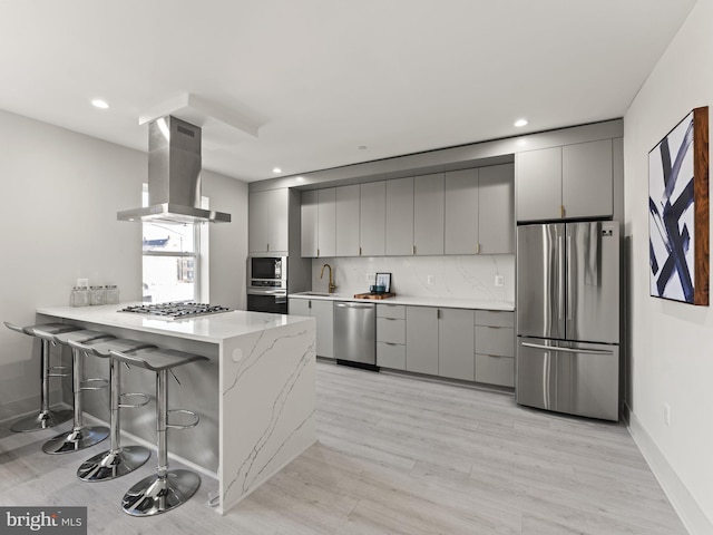 kitchen with ventilation hood, gray cabinets, a kitchen bar, kitchen peninsula, and stainless steel appliances