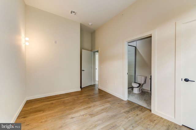 unfurnished bedroom with light wood-type flooring and ensuite bath