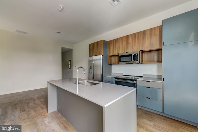 kitchen featuring stainless steel appliances, a kitchen island with sink, light hardwood / wood-style floors, and sink