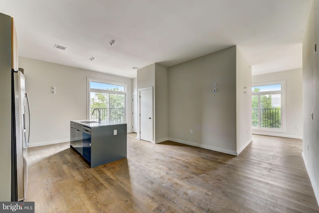 kitchen featuring sink, an island with sink, a healthy amount of sunlight, and dark hardwood / wood-style floors