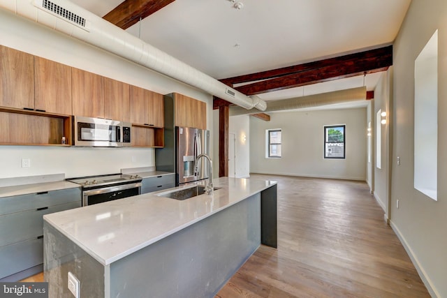 kitchen featuring beamed ceiling, a large island with sink, stainless steel appliances, and sink