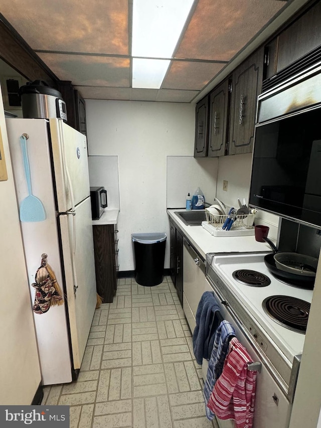 kitchen featuring a paneled ceiling, white appliances, and sink