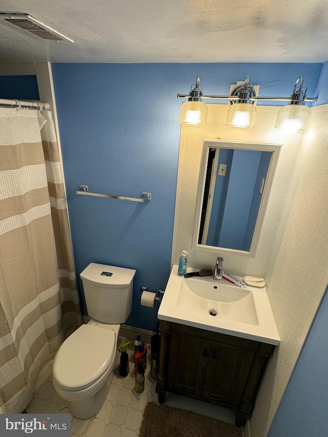 bathroom featuring tile patterned flooring, vanity, and toilet