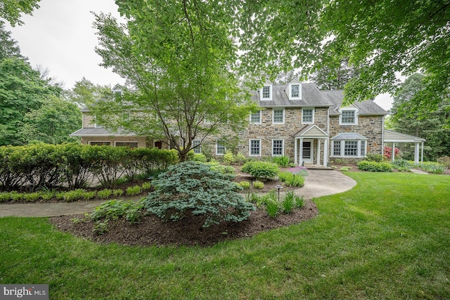 shingle-style home featuring stone siding and a front lawn