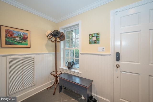 entryway with tile patterned flooring, a wainscoted wall, and crown molding