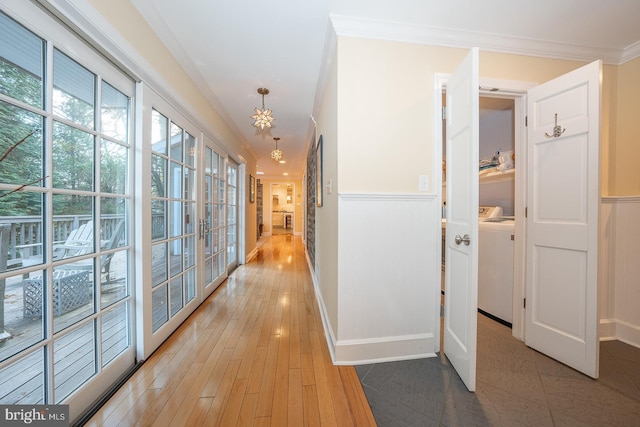 hall with washing machine and dryer, light wood-style flooring, a wainscoted wall, french doors, and crown molding