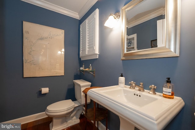 half bathroom featuring toilet, baseboards, crown molding, and wood finished floors