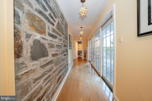 hall featuring baseboards, ornamental molding, wood finished floors, and french doors