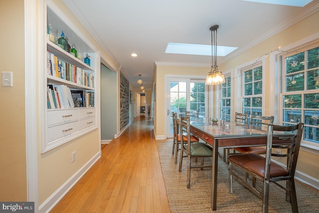 dining space featuring recessed lighting, a skylight, baseboards, light wood-type flooring, and crown molding