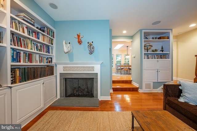 living area featuring recessed lighting, a fireplace, light wood-style flooring, and baseboards