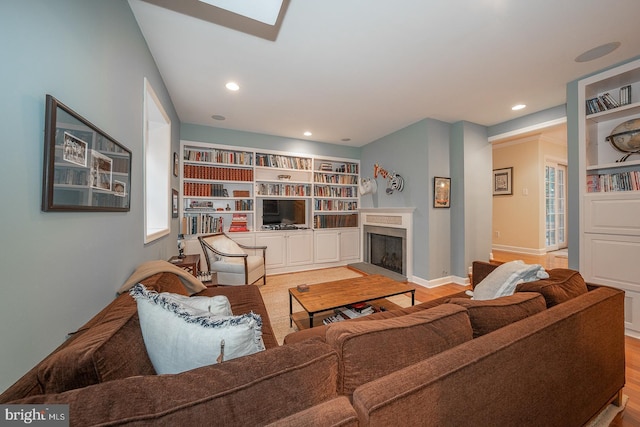 living room featuring a fireplace with raised hearth, light wood finished floors, recessed lighting, and baseboards