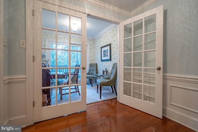 entryway with ornamental molding, wood finished floors, french doors, and wallpapered walls