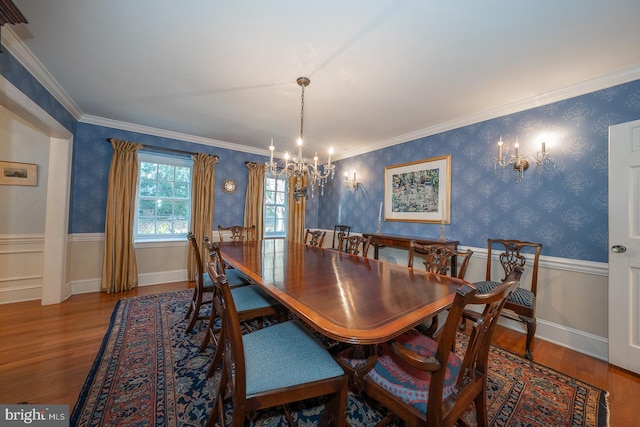 dining room with crown molding, wainscoting, wood finished floors, a chandelier, and wallpapered walls