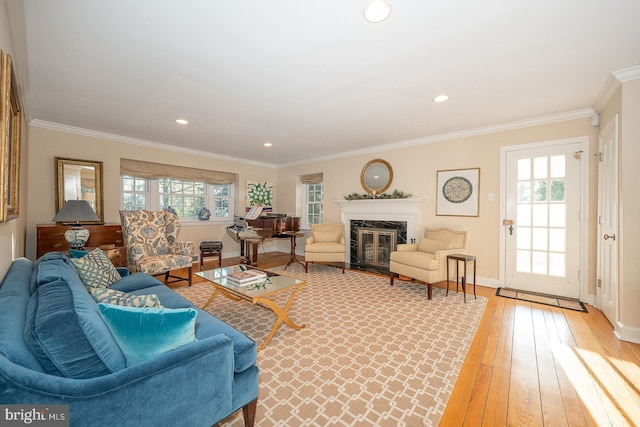 living area featuring crown molding, recessed lighting, a premium fireplace, wood finished floors, and baseboards