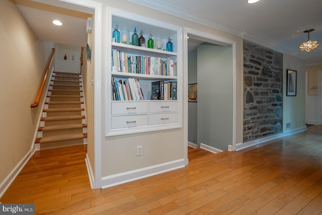 hall featuring recessed lighting, ornamental molding, light wood-type flooring, baseboards, and stairs