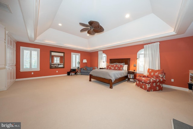 bedroom with visible vents, multiple windows, a tray ceiling, and light colored carpet