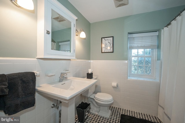 full bathroom with toilet, tile walls, and wainscoting