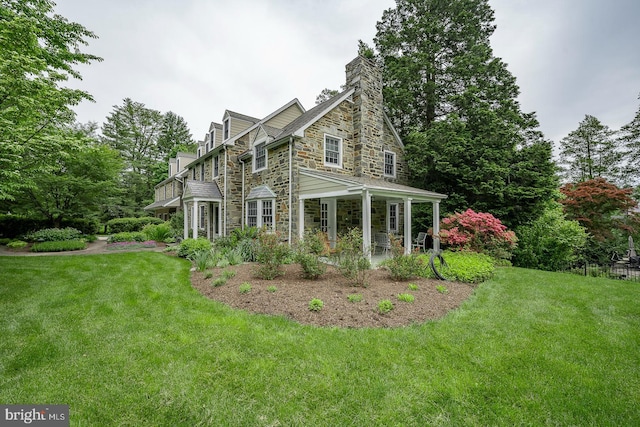 view of front facade with stone siding, a chimney, and a front yard