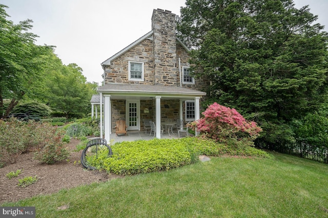 exterior space with stone siding, a chimney, and a front yard