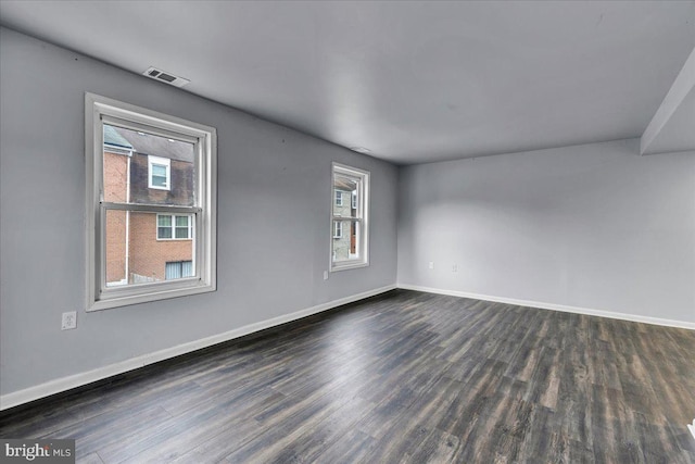 spare room featuring plenty of natural light and dark hardwood / wood-style floors