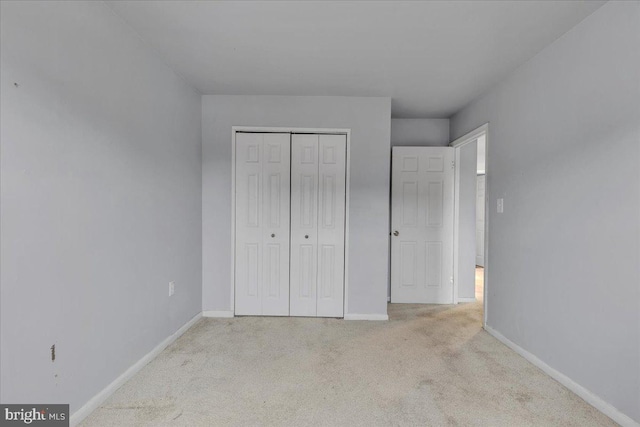 unfurnished bedroom with light carpet and a closet