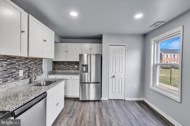 kitchen with sink, light stone countertops, appliances with stainless steel finishes, dark hardwood / wood-style flooring, and white cabinetry