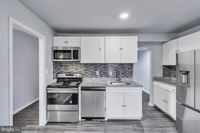 kitchen featuring light stone countertops, white cabinetry, sink, stainless steel appliances, and backsplash