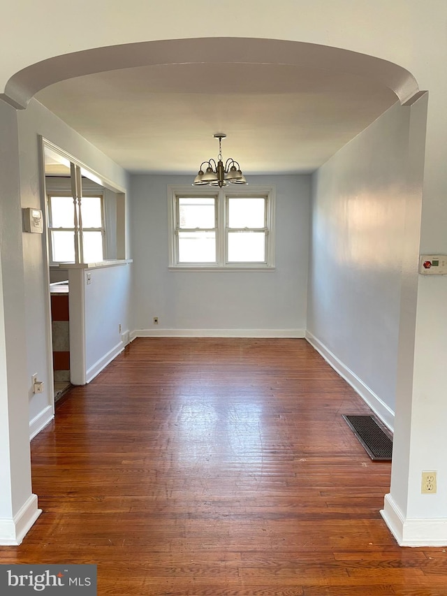 unfurnished room with dark wood-type flooring and a notable chandelier