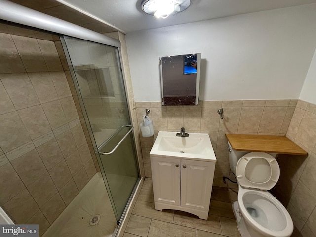 bathroom featuring tile patterned floors, walk in shower, vanity, tile walls, and toilet