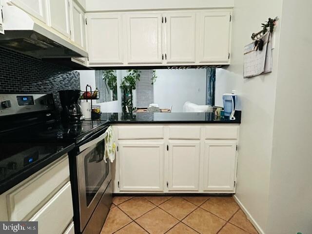 kitchen with white cabinets, decorative backsplash, light tile patterned flooring, and stainless steel range with electric cooktop