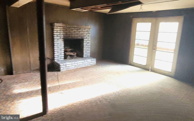 unfurnished living room with carpet flooring, wood walls, a fireplace, and beam ceiling