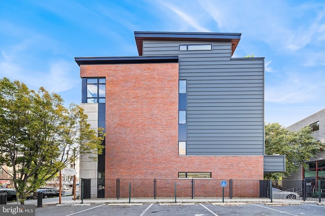 view of building exterior featuring uncovered parking and fence