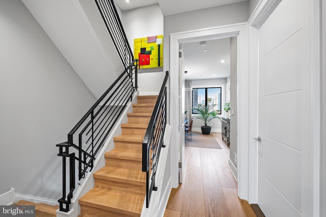 stairway with baseboards, wood finished floors, and recessed lighting