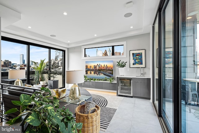 living area featuring wine cooler, bar, a tray ceiling, and light tile patterned floors