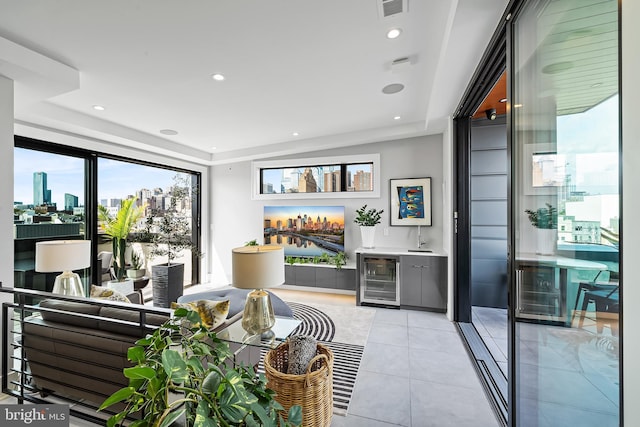 living room featuring a tray ceiling, a dry bar, visible vents, light tile patterned flooring, and beverage cooler