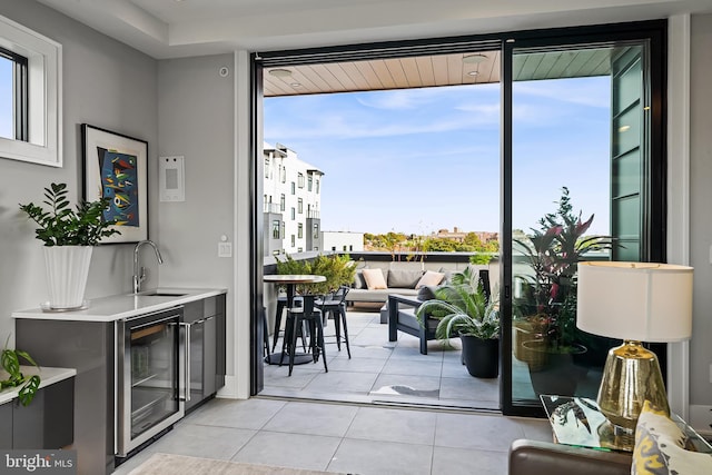 entryway with light tile patterned floors, wine cooler, and a sink