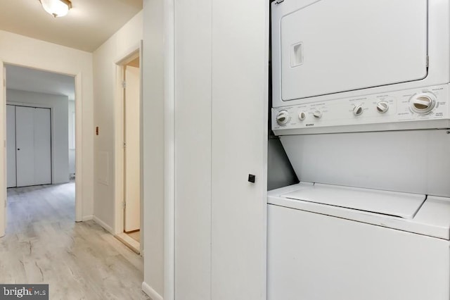 laundry area with light hardwood / wood-style flooring and stacked washer and clothes dryer