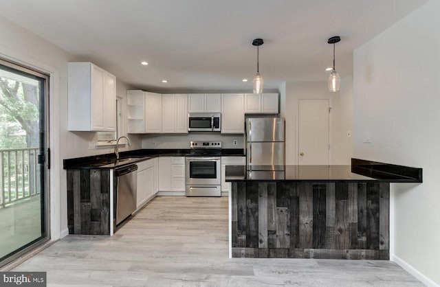 kitchen featuring light hardwood / wood-style floors, white cabinetry, pendant lighting, and appliances with stainless steel finishes