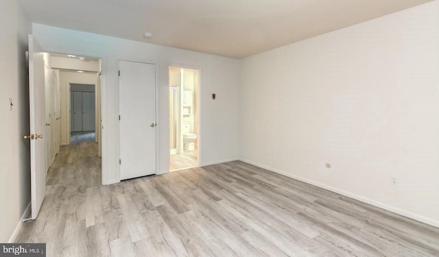 unfurnished bedroom featuring ensuite bathroom and light hardwood / wood-style flooring