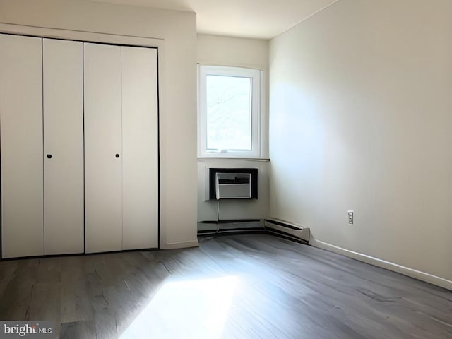 unfurnished bedroom with an AC wall unit, a closet, and hardwood / wood-style floors