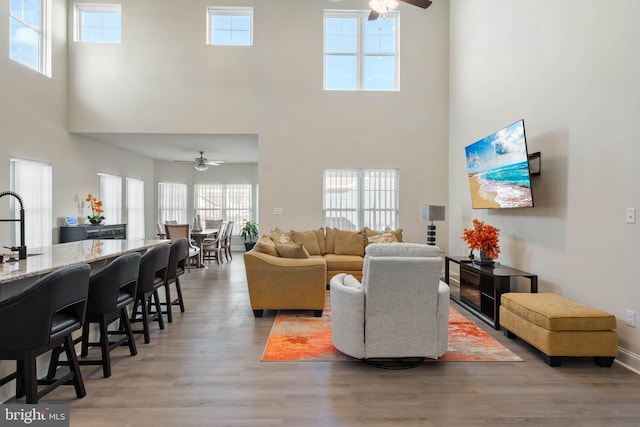 living room with ceiling fan, plenty of natural light, and a high ceiling