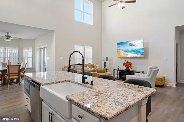 kitchen featuring hardwood / wood-style floors, dishwasher, a high ceiling, sink, and white cabinetry