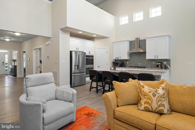 living room with light hardwood / wood-style flooring, a high ceiling, and sink