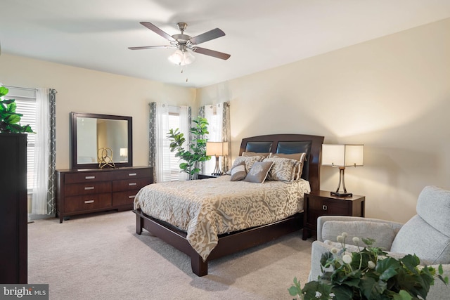 bedroom with light carpet, multiple windows, and ceiling fan