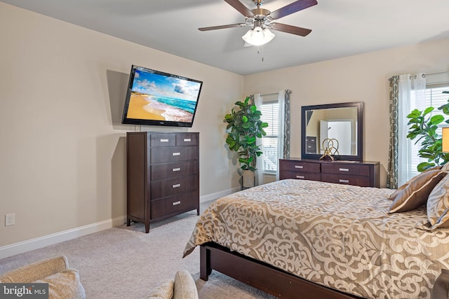 bedroom with multiple windows, ceiling fan, and light carpet