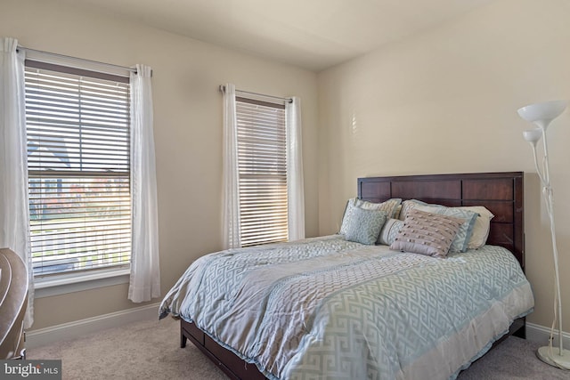 bedroom with light colored carpet and multiple windows