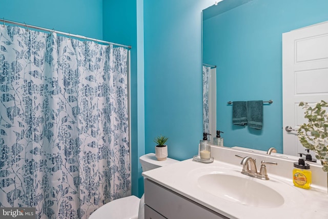 bathroom with walk in shower, vanity, and toilet