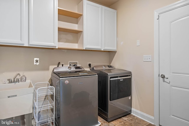 laundry area featuring cabinets, light tile patterned floors, sink, and washing machine and clothes dryer