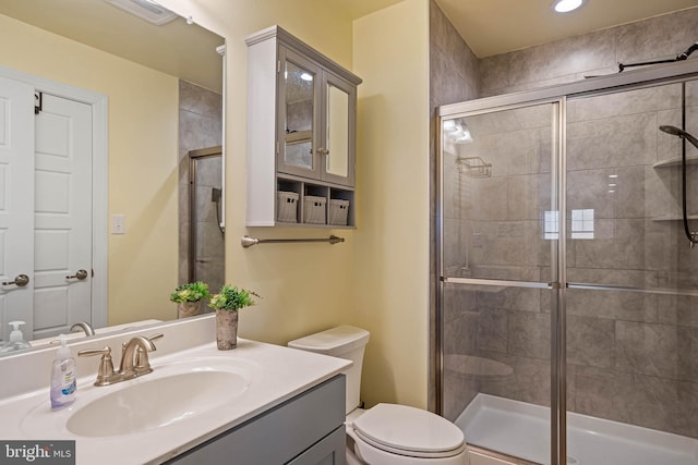 bathroom featuring vanity, toilet, and a shower with shower door