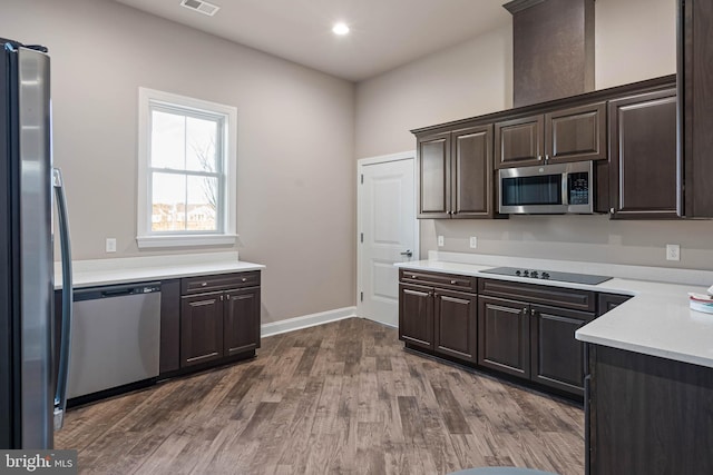 kitchen with dark hardwood / wood-style flooring, stainless steel appliances, and dark brown cabinets